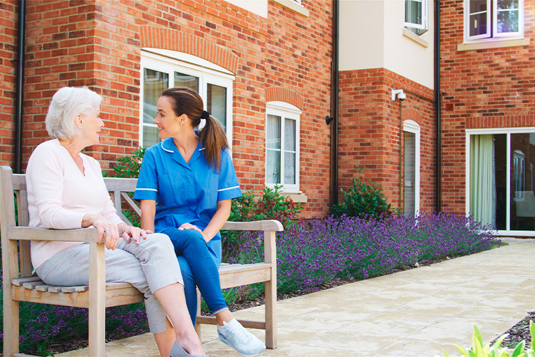 senior woman sitting on bench and talking with nur 2025 03 18 23 13 15 utc | Dunham Care Homes